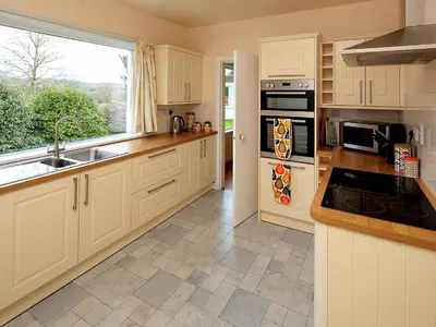 a kitchen with white cabinets and a sink and a window at Mountain Cross in Gatehouse of Fleet