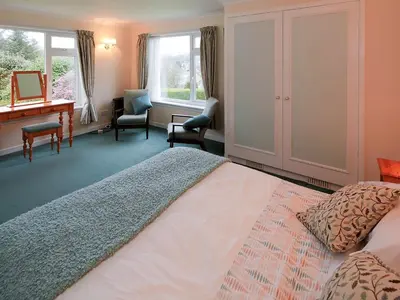 a bedroom with a bed and a desk and windows at Mountain Cross in Gatehouse of Fleet