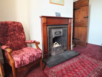 a living room with a chair and a fireplace at Olafs Cottage in Garlieston