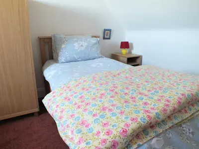 a bedroom with a bed with a floral bedspread at Olafs Cottage in Garlieston