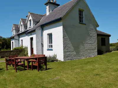 a building with a picnic table in front of it at Olafs Cottage in Garlieston