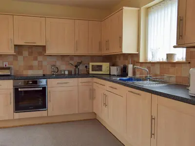 a kitchen with wooden cabinets and a sink and a microwave at Quiet in Whauphill