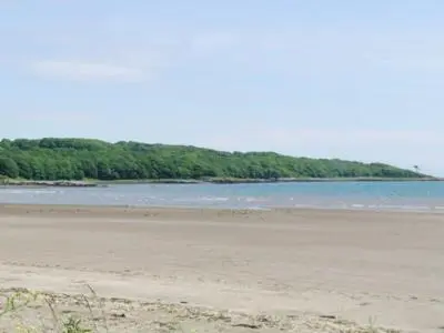an empty beach with trees in the background at The Cottage in Garlieston