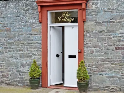 a door in a brick building with two potted plants at The Cottage in Garlieston