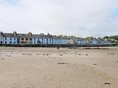 a beach with a row of houses in the background at The Cottage in Garlieston
