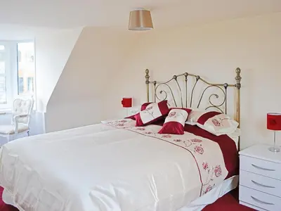 a bedroom with a large white bed with red pillows at Sea-Esta - 28175 in Port William