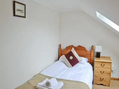 a bedroom with a bed with a wooden headboard and a dresser at The Hen Hoose in Creebridge
