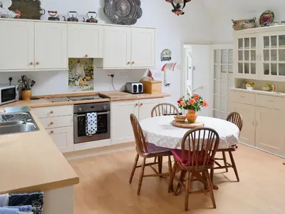 a kitchen with white cabinets and a table with chairs at Holly Cottage - 28140 in Boreland of Colvend