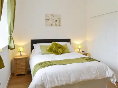 a bedroom with a white bed with yellow pillows at Rose Cottage - 28176 in Fairgirth