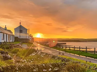 a sunset over a church and a body of water at Gigha in Drummore