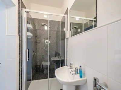 a white bathroom with a shower and a sink at Braefield in Portpatrick