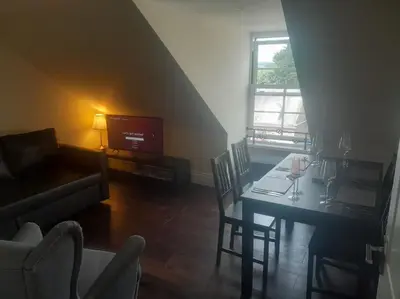 a living room with a table with chairs and a television at Kirkcudbright Holiday Apartments - Apartment G in Kirkcudbright