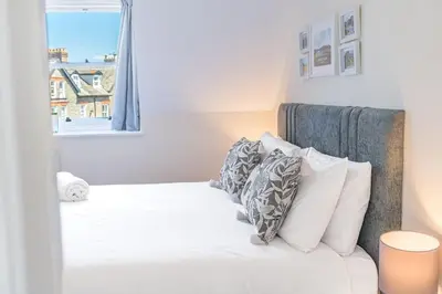 a bedroom with a white bed with pillows and a window at Hazelgrove, Ratcliffe Place, Keswick in Keswick