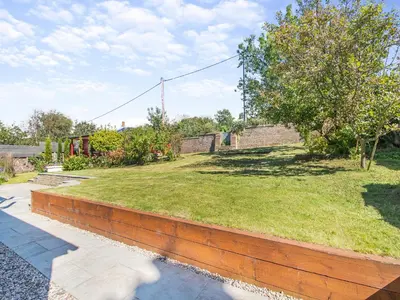 a brick retaining wall next to a field of grass at Aird Cottage in Dunure