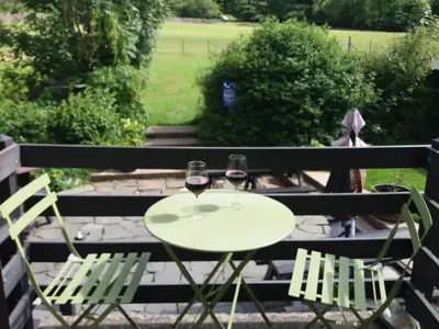two glasses of wine sitting on a table with two chairs at NEWFIELD INN in Broughton in Furness