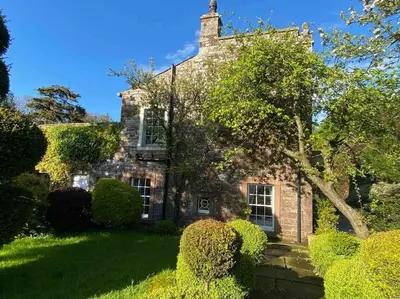 an old stone house with bushes in front of it at Unique Country Estate nr Mountains & Beach in Silloth
