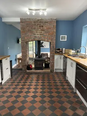 a kitchen with a brick fireplace in a room at Apple Cottage in Wigtown