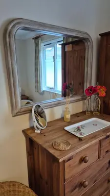 a mirror on top of a wooden dresser with a sink at The Chalets in Eskdale