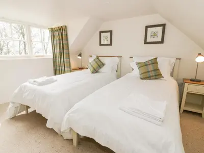 two beds in a room with white sheets at Saltflats Cottage - Rockcliffe in Dalbeattie