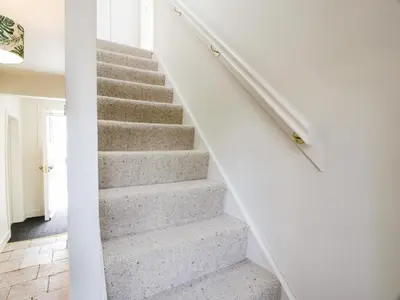 a staircase in a home with white walls and carpet at Saltflats Cottage - Rockcliffe in Dalbeattie