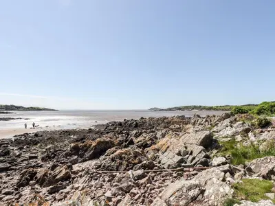 a group of people walking on a rocky beach at Saltflats Cottage - Rockcliffe in Dalbeattie