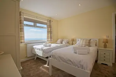 a bedroom with two beds and a window at High Auchenlarie Cottage in Gatehouse of Fleet