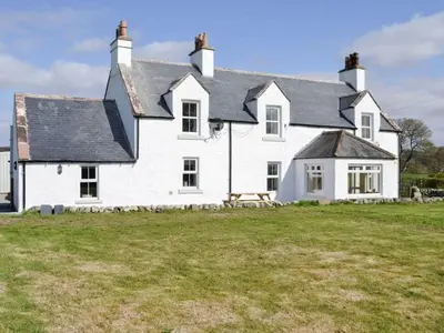 a large white house with a picnic table in a field at Blackloch in Gatehouse of Fleet