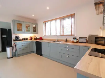 a large kitchen with blue cabinets and a sink at Knockendoch in Dumfries