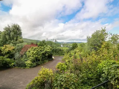 a path through a garden with trees and bushes at Knockendoch in Dumfries