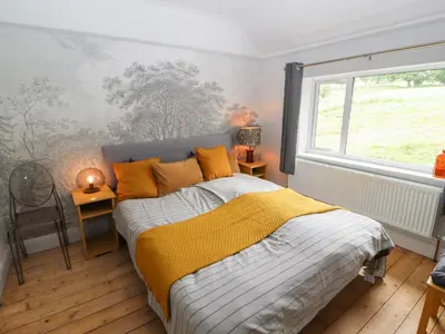 a bedroom with a bed with a yellow blanket and a window at Beech Croft in Keswick