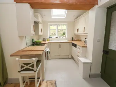 a kitchen with white cabinets and a skylight at Beech Croft in Keswick
