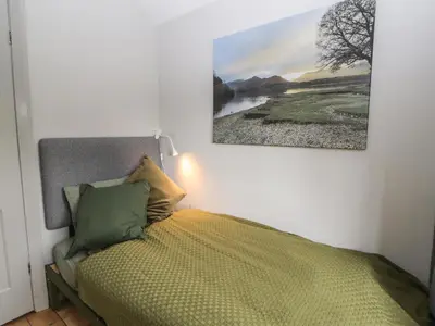 a bedroom with a bed with a painting on the wall at Beech Croft in Keswick