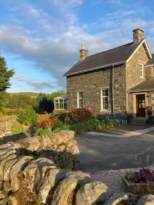 a stone house with a stone wall in front of it at Polharrow in Dalry