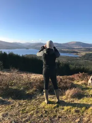 a person standing on a hill looking at a lake at Polharrow in Dalry