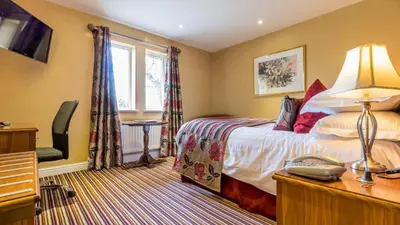 a hotel room with a bed and a phone on a desk at Hunday Manor Country House Hotel in Workington