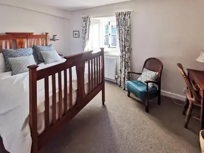 a bedroom with a bed and a chair and a window at Earsdon Cottage in Ireby
