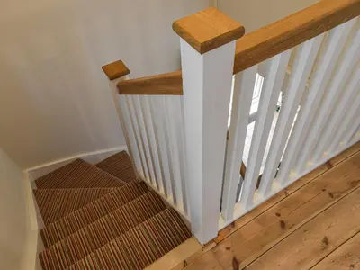 a staircase with white railings and a wooden stair case at Earsdon Cottage in Ireby