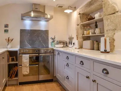 a kitchen with white cabinets and a stove top oven at Earsdon Cottage in Ireby
