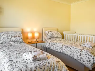 a bedroom with two beds and two lamps on a table at Little Glengyre Farm in Kirkcolm