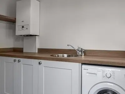 a kitchen with a sink and a washing machine at Southways Cottage in Cumwhinton