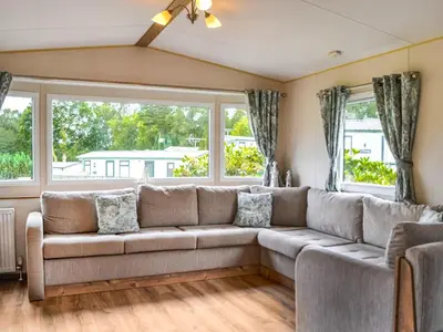 a living room with a couch and two windows at The Beachcomber in Palnackie