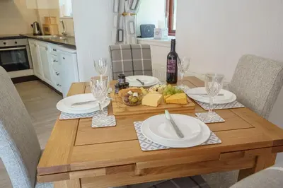 a wooden table with plates and wine glasses on it at Jane Welsh Cottage in Thornhill