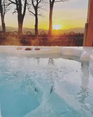 a hot tub with a sunset in the background at Dalgarnock Cottage in Thornhill