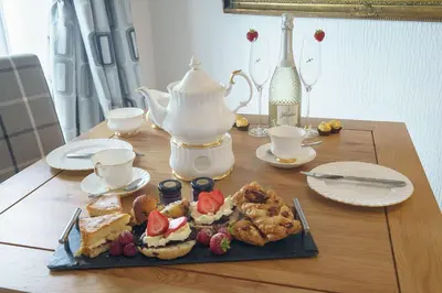 a table with a plate of food and a tea kettle at Dalgarnock Cottage in Thornhill