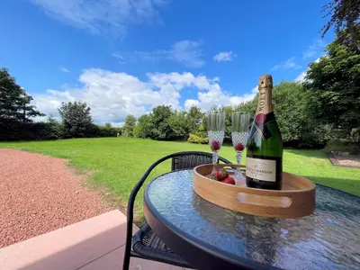 a bottle of wine and two glasses on a table at Spectacular 7BR House Hot Tub and Gardens in Gretna - Pass the Keys in Gretna Green