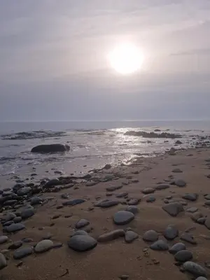 a beach with rocks on the sand and the ocean at Serenity in Monreith
