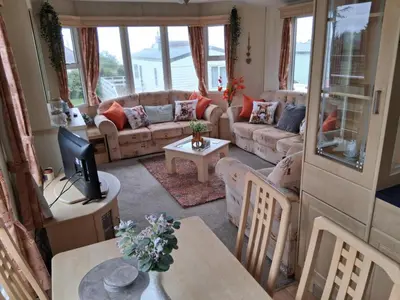 a living room with couches and a tv and a table at Serenity in Monreith