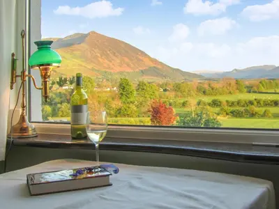 a glass of wine sitting on a table next to a window at High Spy in Bassenthwaite