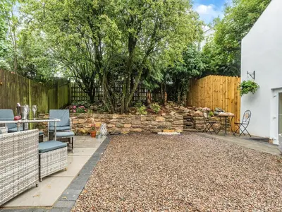 a backyard with a stone wall and a table and chairs at The Nook - Uk44735 in Tallentire