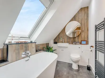 a bathroom with a large tub and a skylight at Seascape Barn in Kirkcolm